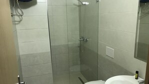 Une salle de bain avec une douche, des toilettes et un lavabo.