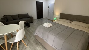 Une chambre moderne avec un grand lit, un canapé, une table à manger avec des chaises et une armoire.