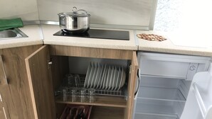 Une cuisine équipée d’un lave-vaisselle encastré, avec une casserole sur la cuisinière et un égouttoir à vaisselle.