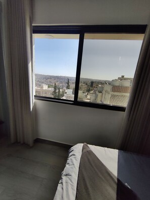 Enjoy a city view from the large window, framed by a black border and partially covered by a white curtain.