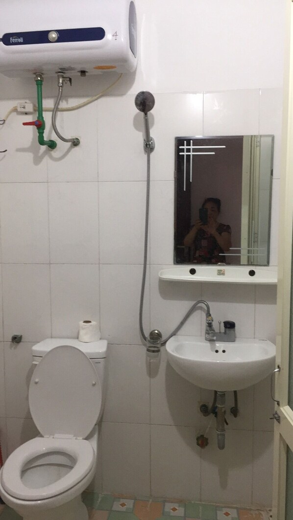 Kylpyhuone, jossa on wc, pesuallas ja peili.