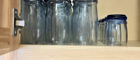 A cabinet with glass jars and a decorative panel.