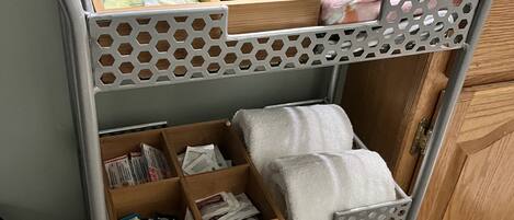 Un chariot en métal doté de plusieurs compartiments pour ranger les articles de toilette, les serviettes et les produits en papier.