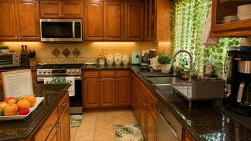 A kitchen with wooden cabinets, a stainless steel microwave, a stove, and a coffee maker.