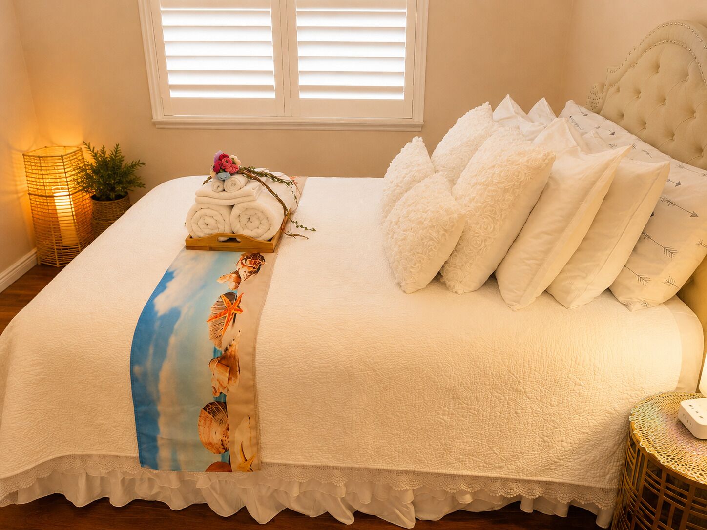 A neatly made bed with a white duvet, rolled towels, and a decorative pillow arrangement.