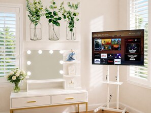 A room with a vanity, mirror, and a television displaying a Roku TV interface. - Balloons and Wine (Murrieta)