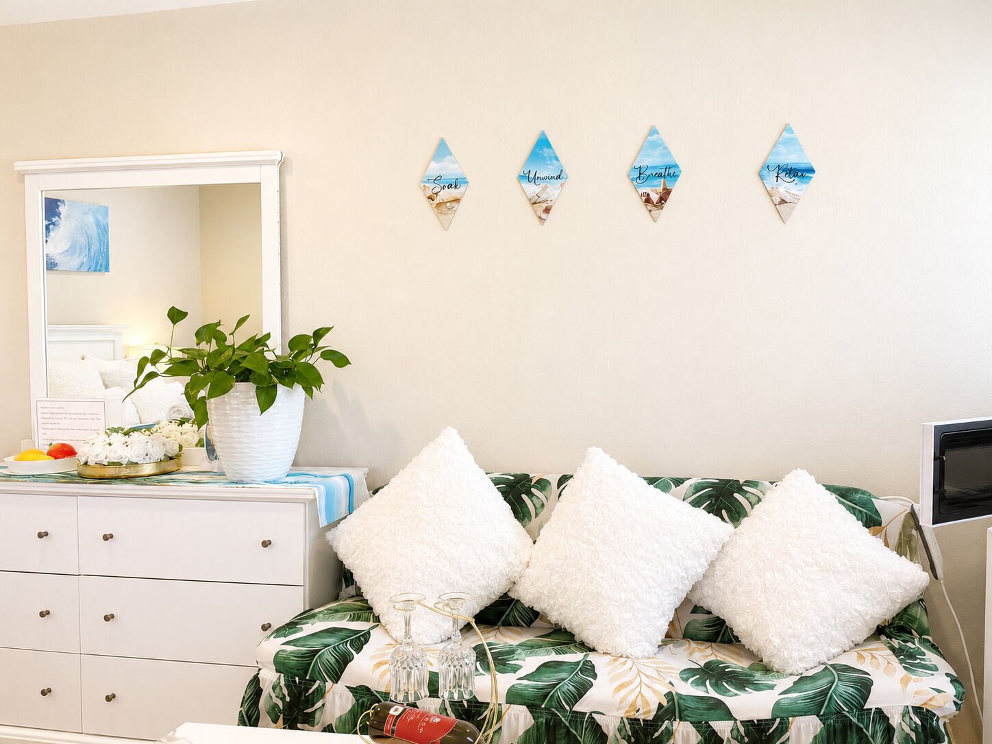 Una camera da letto con un letto, una cassettiera, uno specchio, una pianta in vaso e decorazioni a parete.