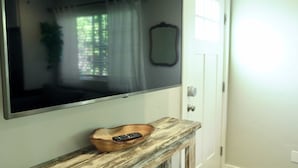 Un televisor de pantalla plana montado en la pared sobre un mueble bajo de madera con un control remoto.