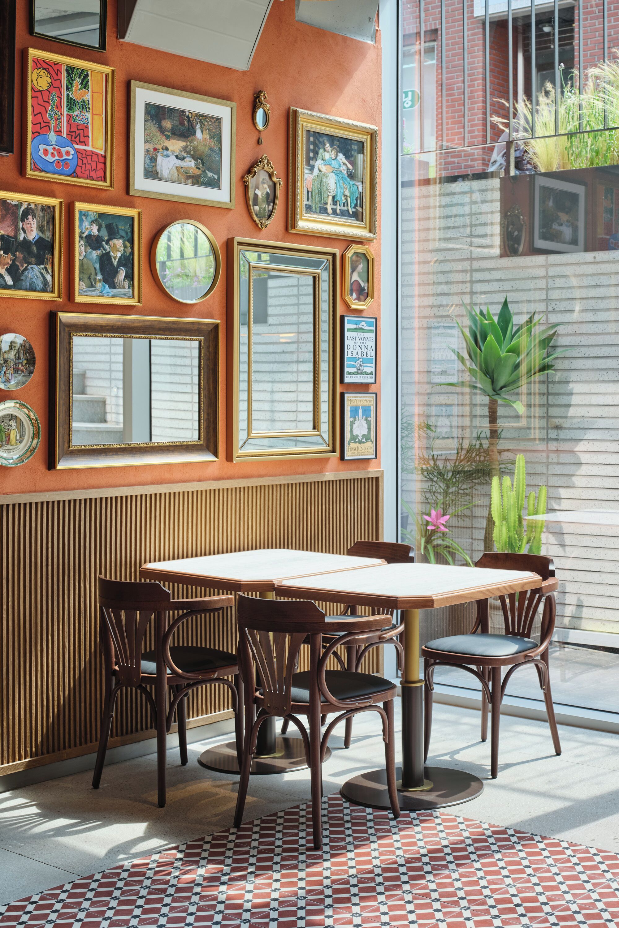 Un comedor con una mesa y sillas de madera, rodeado de cuadros en la pared.