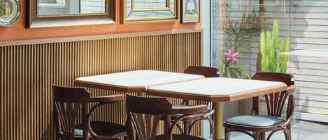 Un comedor con una mesa y sillas de madera, rodeado de cuadros en la pared.