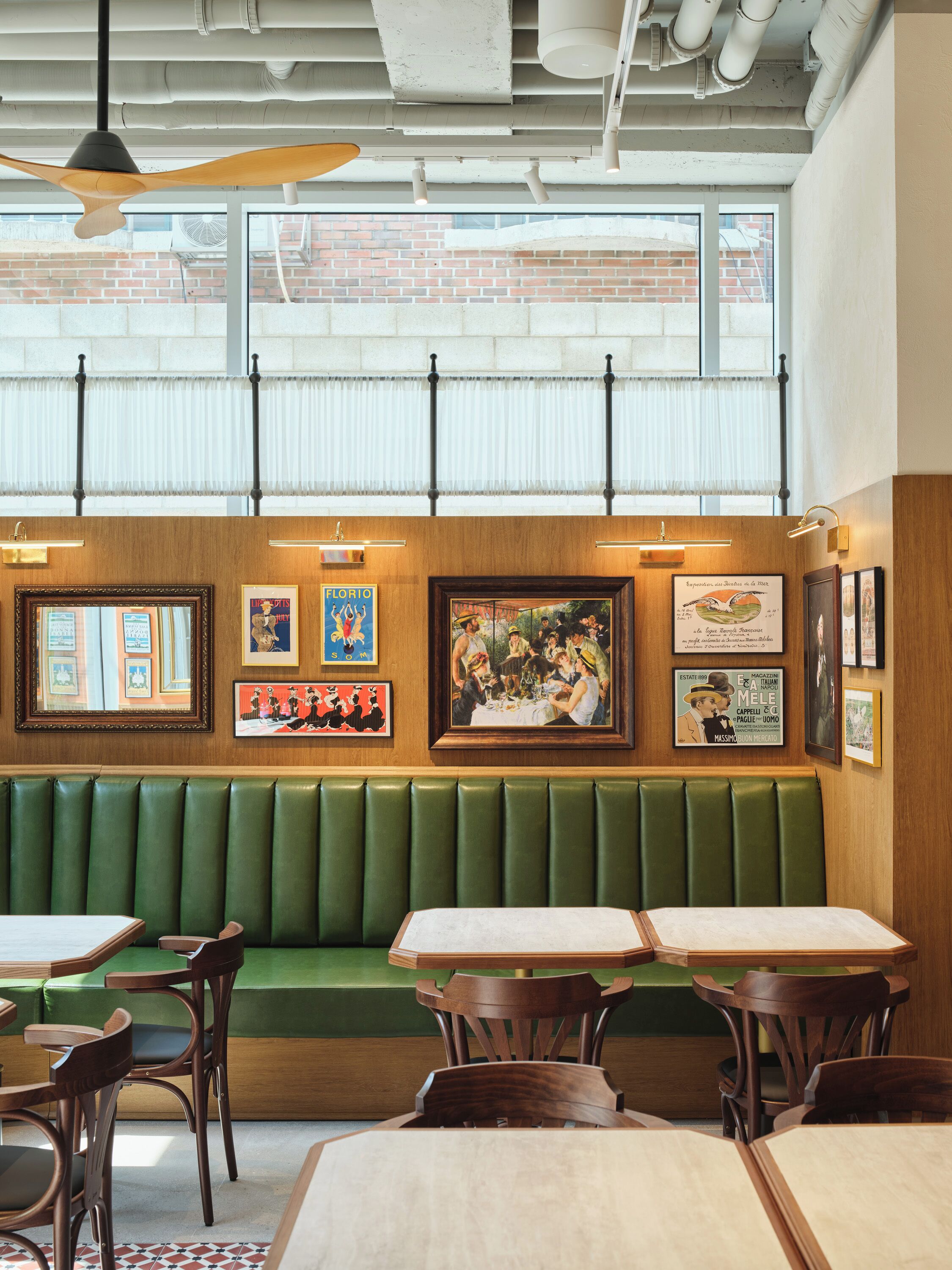 A restaurant interior with wooden booths, tables, and artwork on the walls.