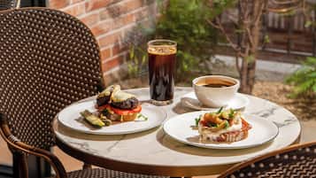 Una mesa redonda con dos platos de comida, un vaso de bebida helada y una taza de café.