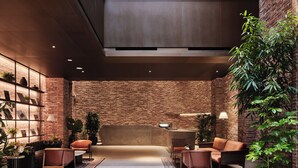 A spacious lobby with a high ceiling and exposed brick walls, featuring a seating area with leather sofas and a coffee table. - ANANTI AT GANGNAM (Seoul)
