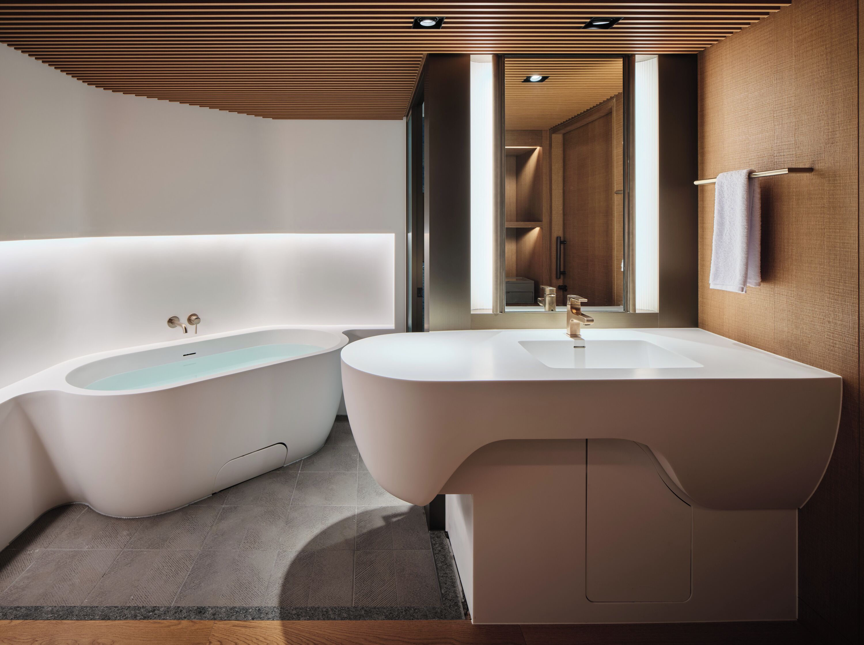 Un baño moderno con una bañera independiente, un tocador con lavamanos y un espejo.