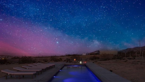 A swimming pool with lounge chairs and a view of the night sky.