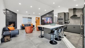 A modern kitchen with a central island, grey cabinetry, and stainless steel appliances.