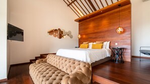 A modern bedroom with a large bed, wooden paneling on the wall, and a unique light fixture. - Private Pool • Garden Views • Two King Bedrooms (Canggu)