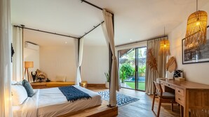 Ein geräumiges Schlafzimmer mit einem großen Bett, einem Holztisch und Blick ins Freie.