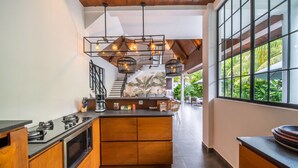 Une cuisine moderne dotée d’un îlot central, de meubles en bois et offrant une vue sur un escalier menant à un autre niveau.