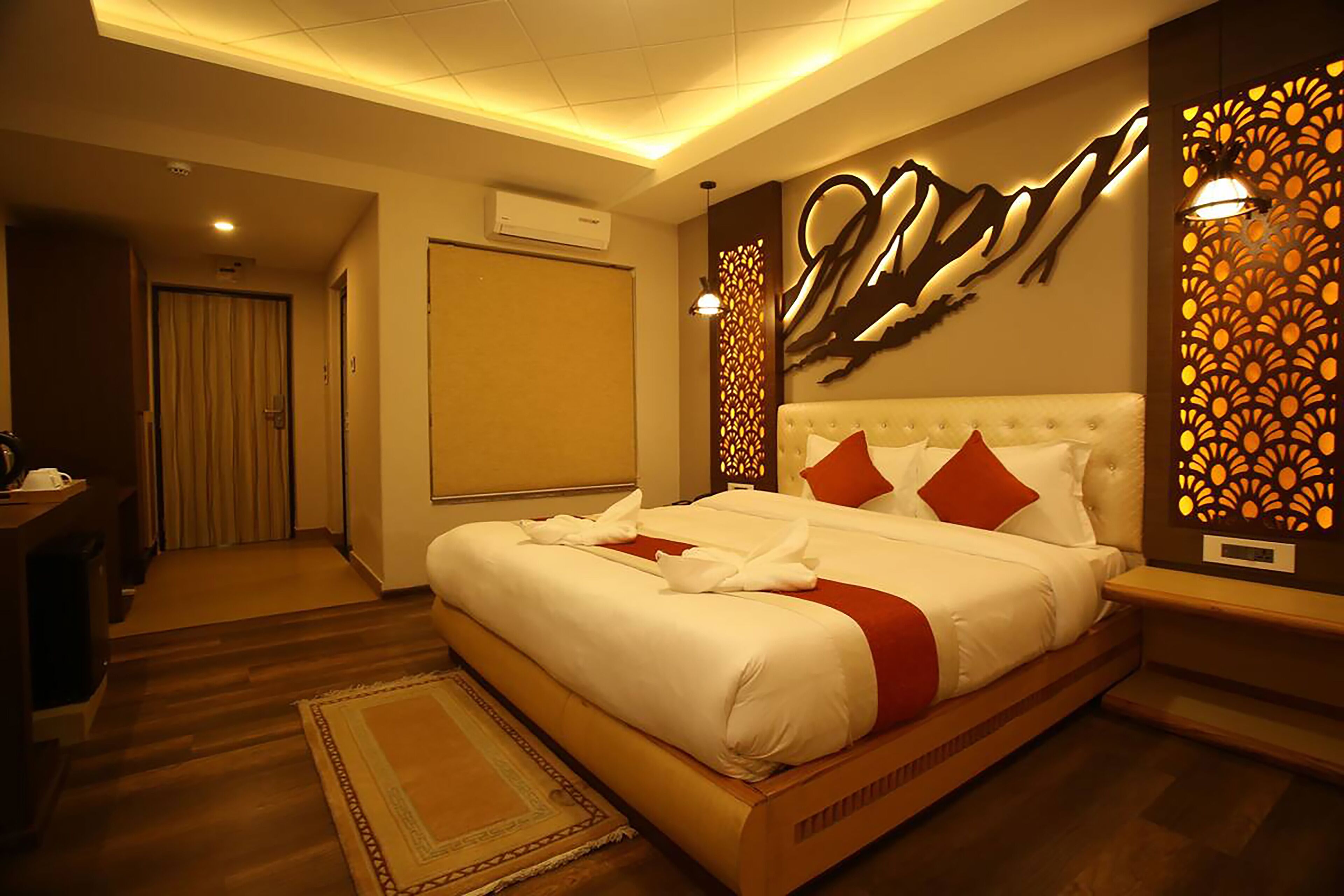 A hotel room with a large bed, a desk, and a wardrobe.