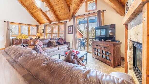 A cozy living room with a leather sofa, wooden coffee table, and a television. - Cabins in the Pines #12 by Summit County Mountain Retreats (Keystone)