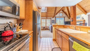 A modern kitchen with wooden cabinets, a stainless steel refrigerator, a microwave, and a red kettle. - Cabins in the Pines #12 by Summit County Mountain Retreats (Keystone)