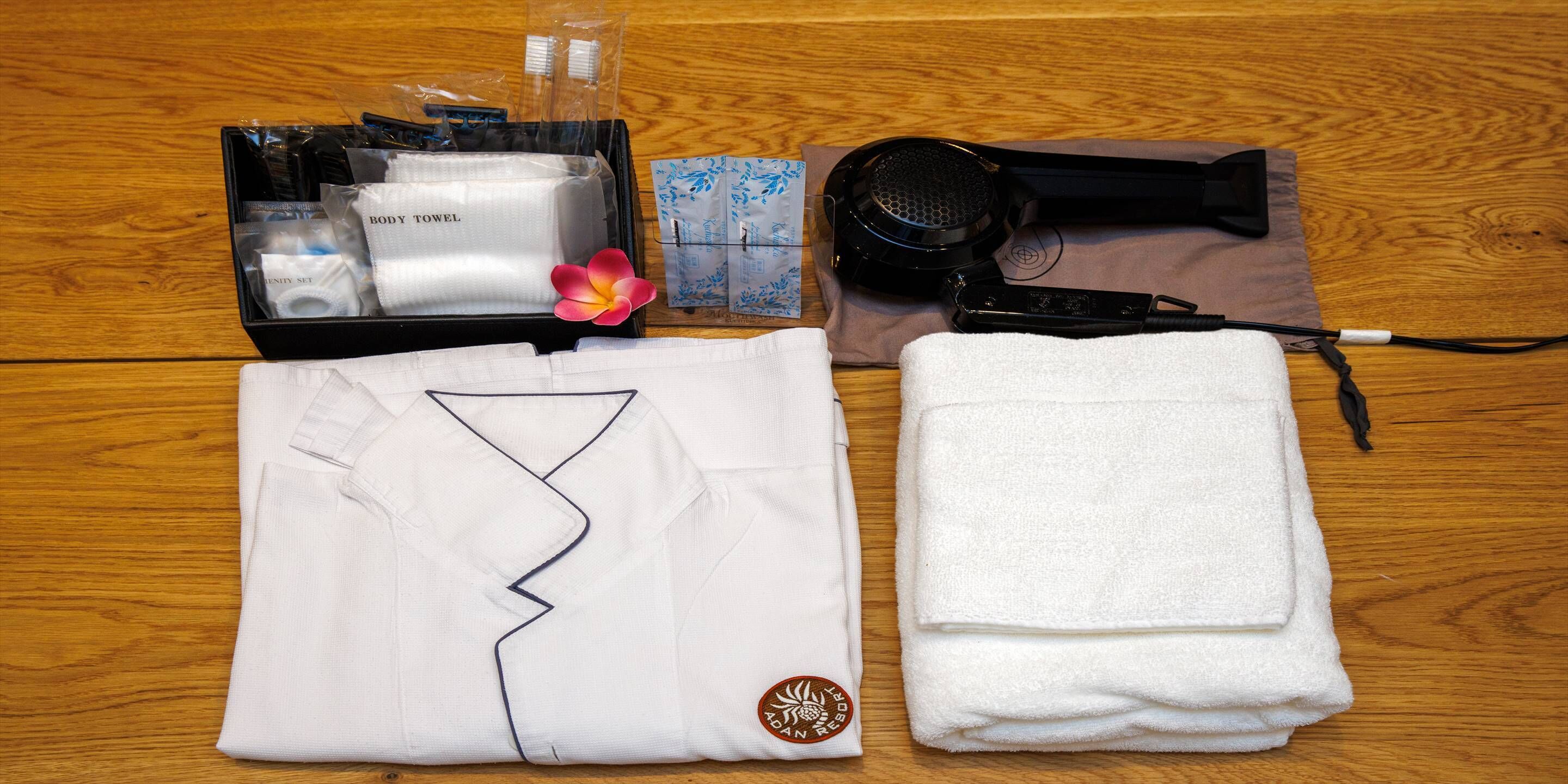 Un conjunto ordenado de artículos de aseo personal y una camisa blanca doblada sobre una superficie de madera.
