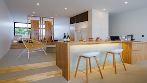 A modern kitchen with a central island, bar stools, and a dining area with a view. - ADAN RESORT Sky Villa luxury Suite (Motobu)