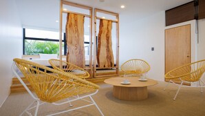 A modern room with a round wooden table, four wicker chairs, and a large window with a view of greenery. - ADAN RESORT Sky Villa luxury Suite (Motobu)