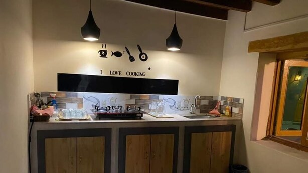 A kitchen with wooden cabinets, a countertop, and hanging pendant lights. - The Vintage Guest House Skardu  (Skardu)