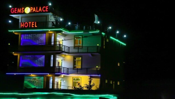 Um edifício de vários andares com a placa 'Gemsopalace Hotel' no topo.