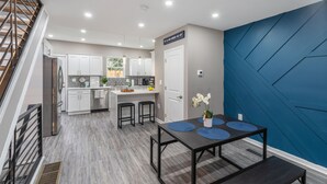 Una cocina moderna con armarios blancos, una isla integrada y una pared de acento azul.