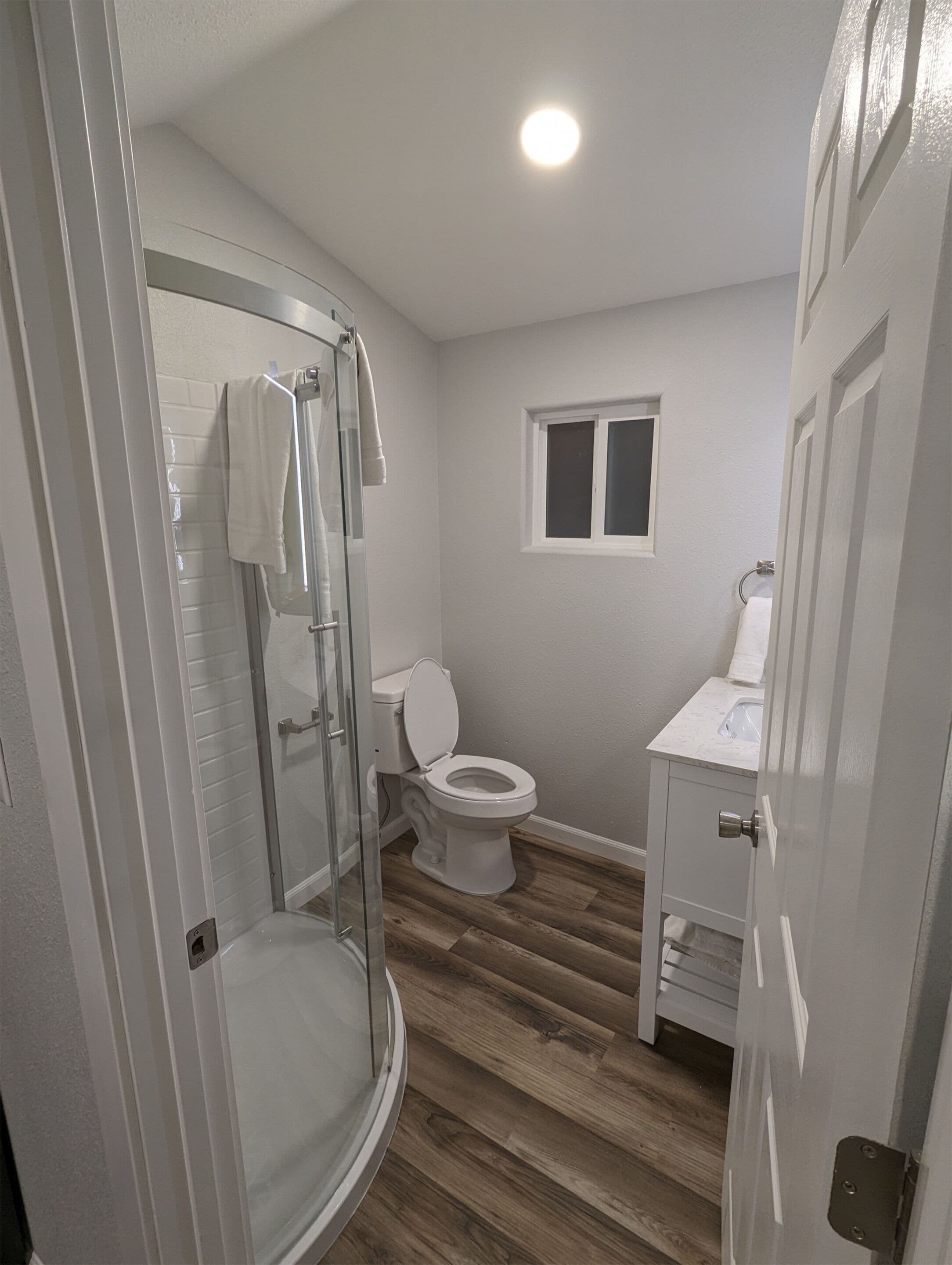 A bathroom with a glass shower enclosure, a toilet, and a sink.
