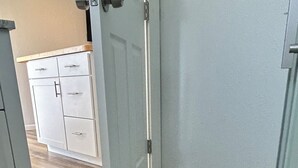 A room with a wooden floor, a white door, and a white cabinet with drawers.