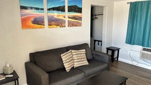 A living room with a sofa, a coffee table, and three paintings on the wall.