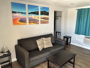 A living room with a sofa, a coffee table, and three paintings on the wall. - Snowy Mountain Inn (Saratoga)