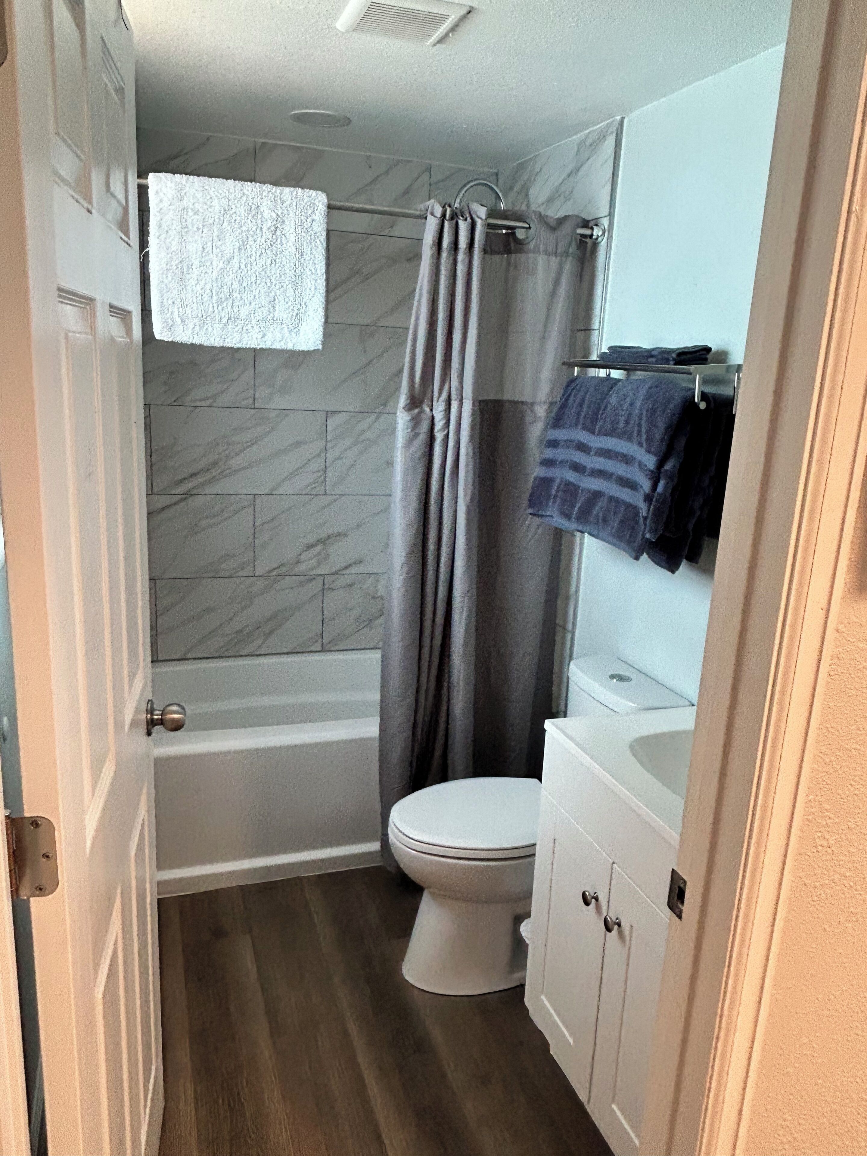 A bathroom with a bathtub, toilet, and a vanity with a mirror.
