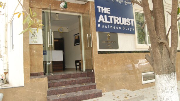 La entrada a The Altruist Business Stays, con escalones de mármol y un puerta de cristal.