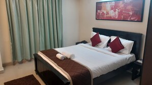 Una habitación de hotel con una cama, una mesita de noche, un teléfono, un tapete marrón y un cuadro en la pared.