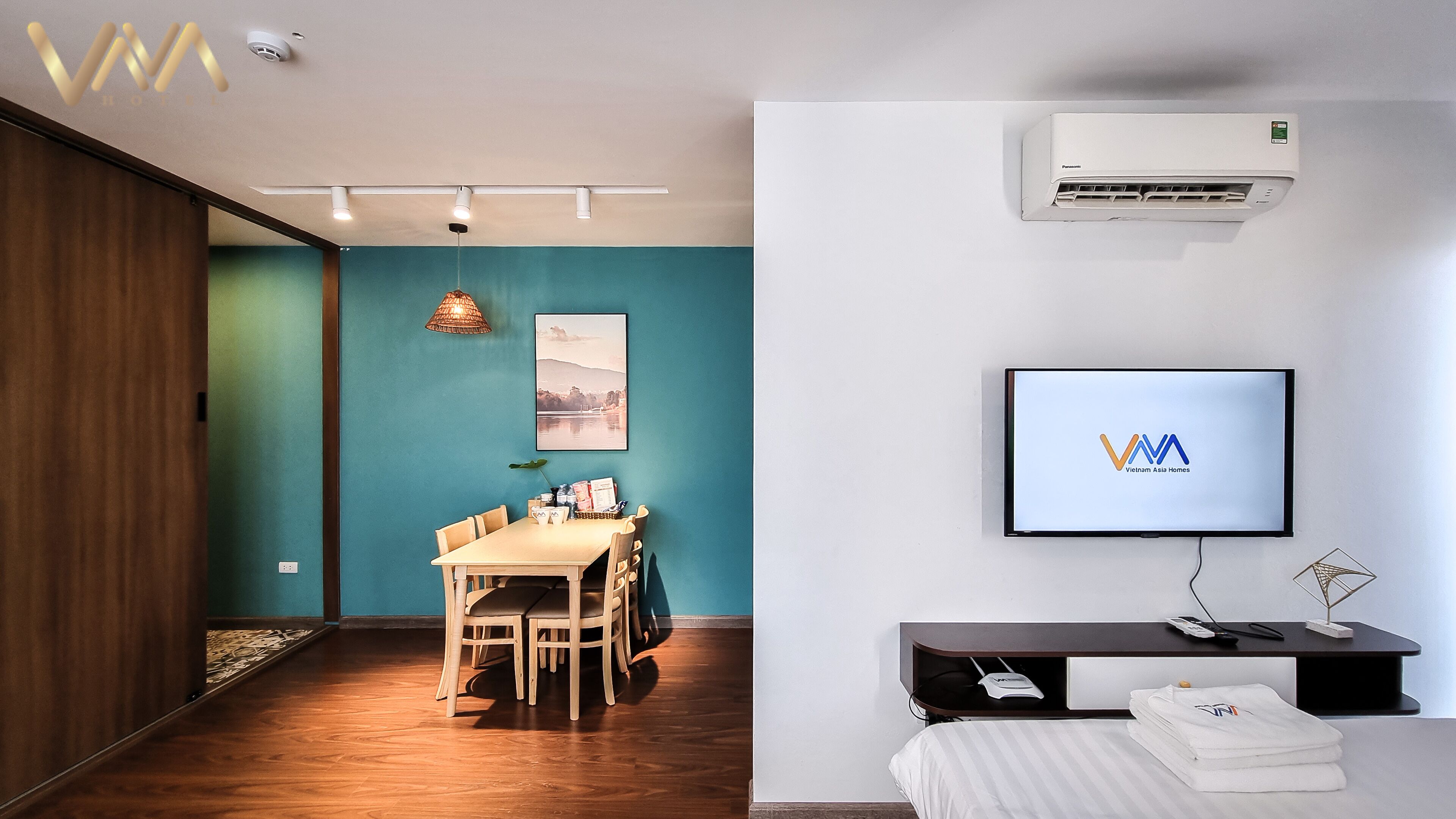 Et moderne hotelværelse med spiseplads, et fladskærms-tv og et klimaanlæg.