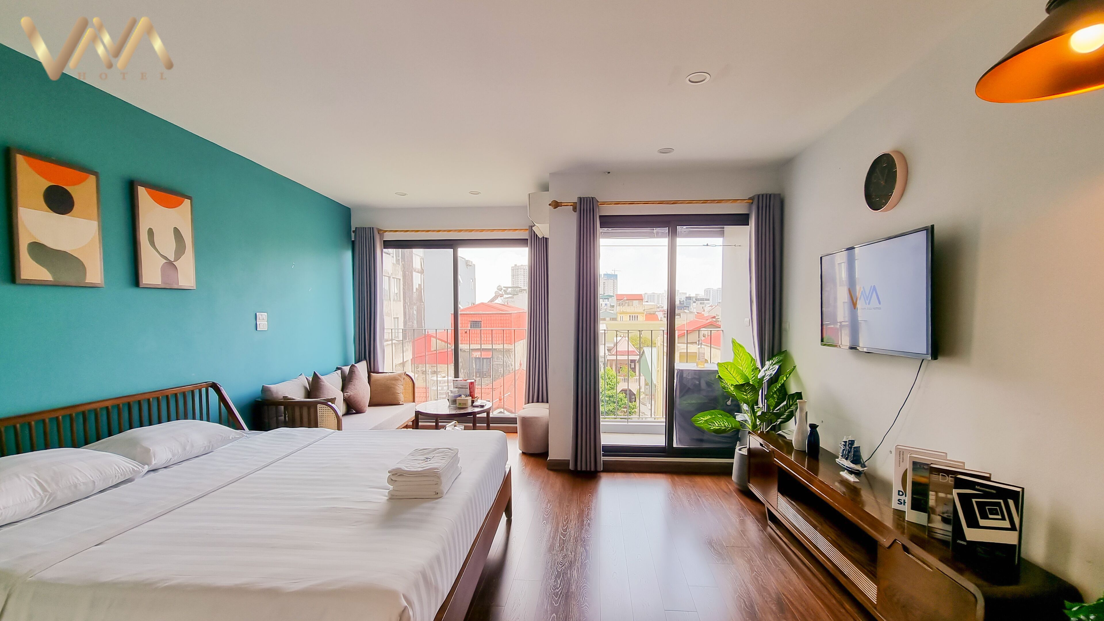 A hotel room with a bed, a sofa, a small table, and a TV.