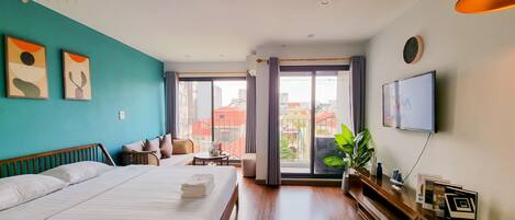 A hotel room with a bed, a sofa, a small table, and a TV.