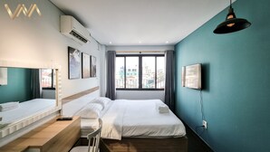 Une chambre d’hôtel avec deux lits, un bureau, une télévision et une fenêtre donnant sur la ville.