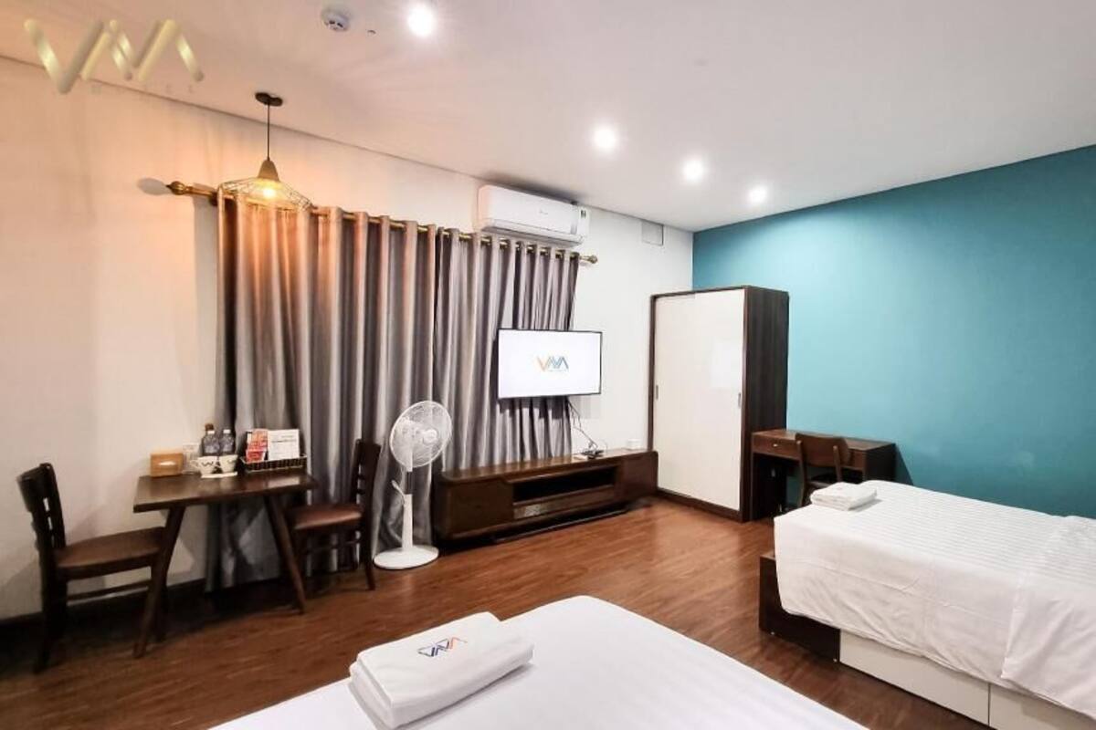 Une chambre d’hôtel comprenant un lit, un bureau avec une chaise, une télévision, une armoire et un ventilateur.