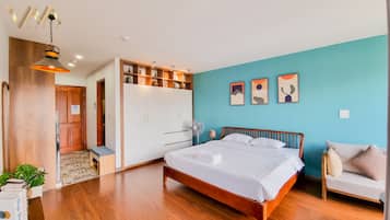 A modern hotel room with a wooden bed, a wardrobe, a desk, and a blue accent wall.