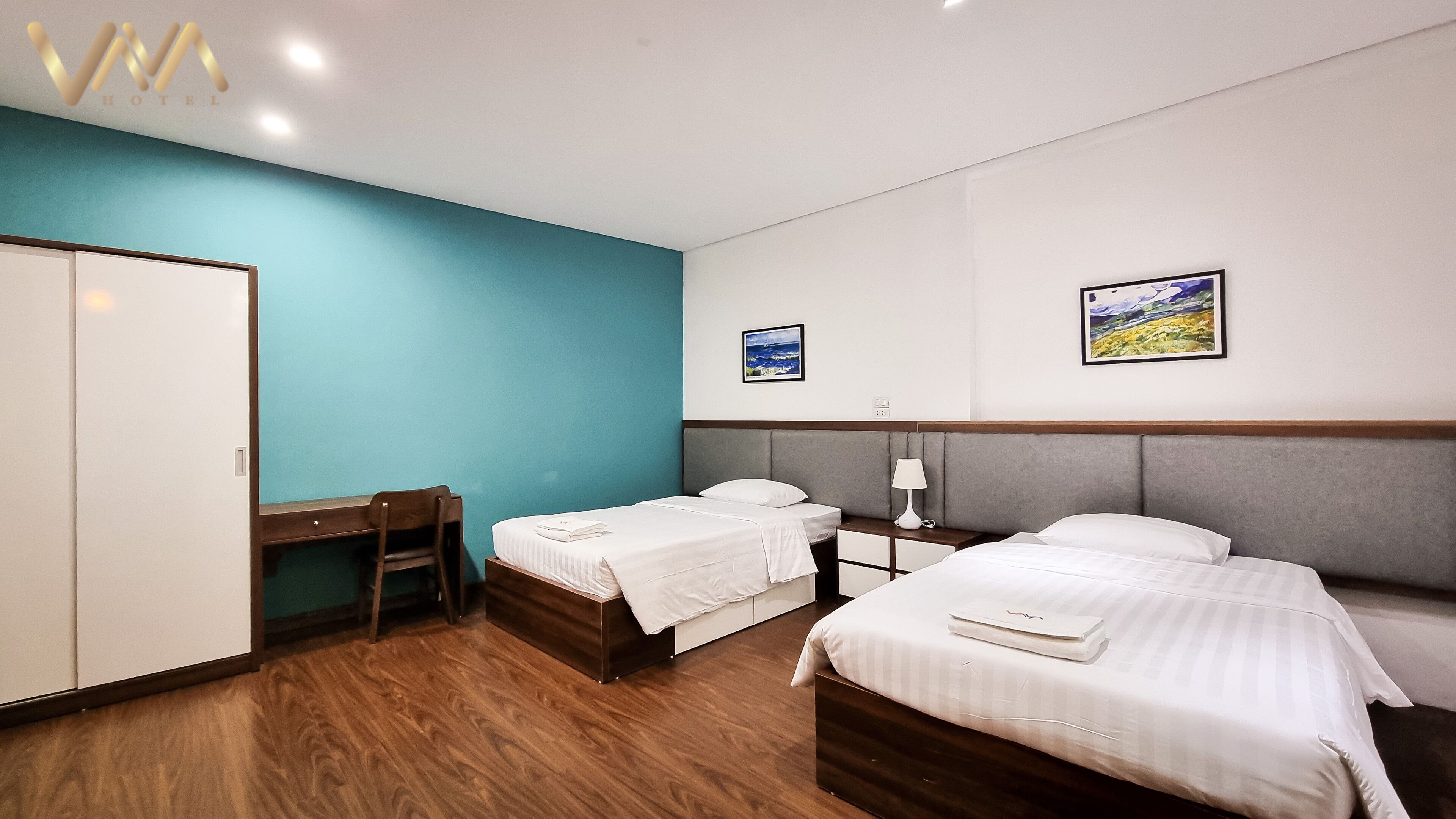 A hotel room with two beds, a desk, and a wardrobe.