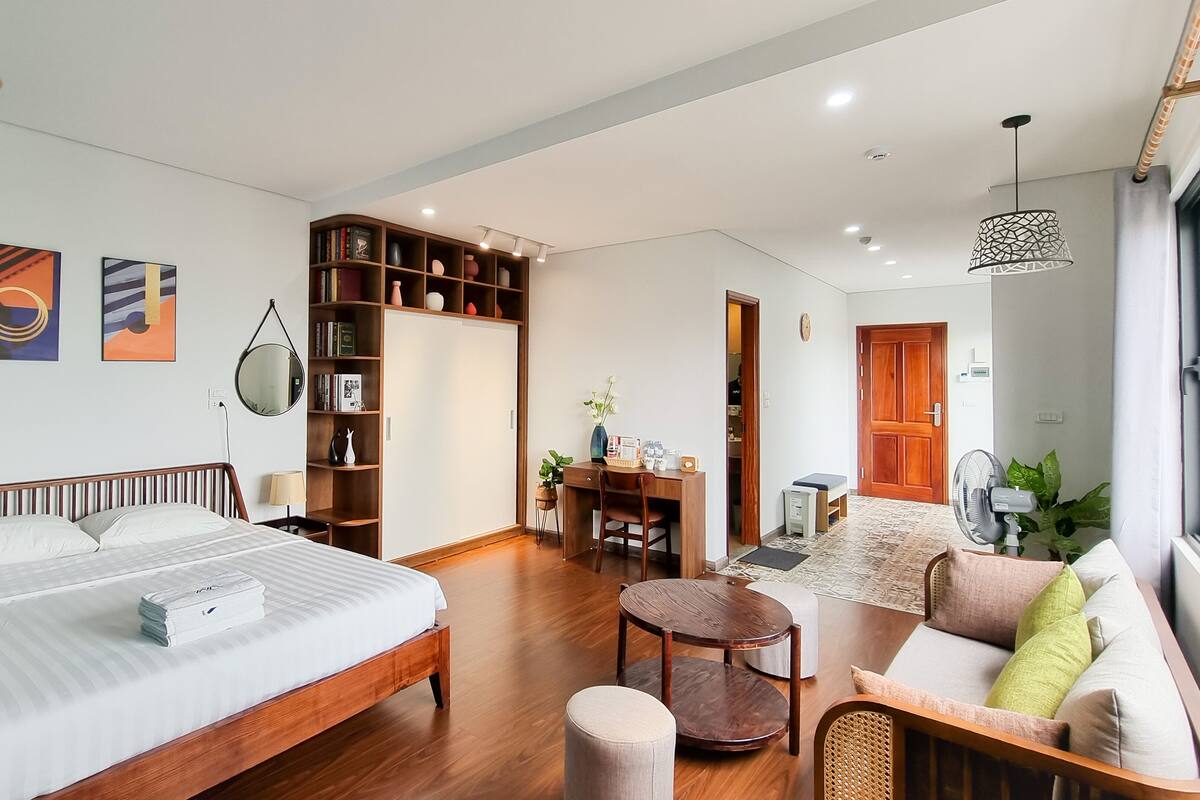 Une chambre d’hôtel moderne équipée d’un grand lit, d’un bureau, d’un canapé et d’une bibliothèque.
