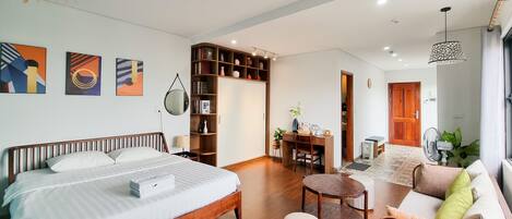 Una habitación de hotel moderna con una cama grande, un escritorio, un sofá y una estantería.