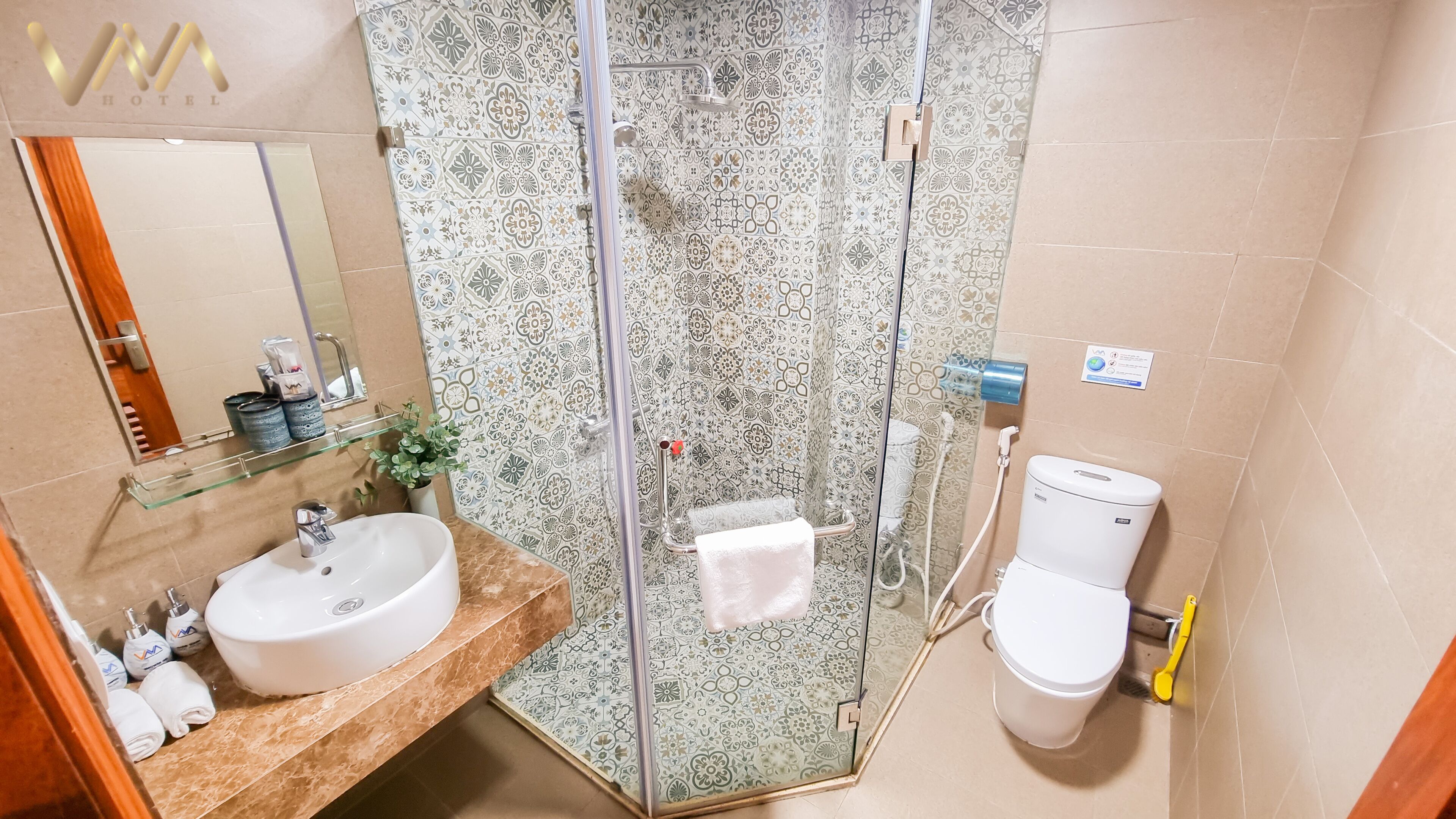 Een badkamer met een douche met glazen wand, een wastafel, toilet en spiegel.