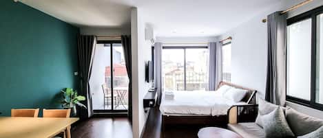Una habitación de hotel con una cama, un sofá, una mesa de comedor y un televisor.